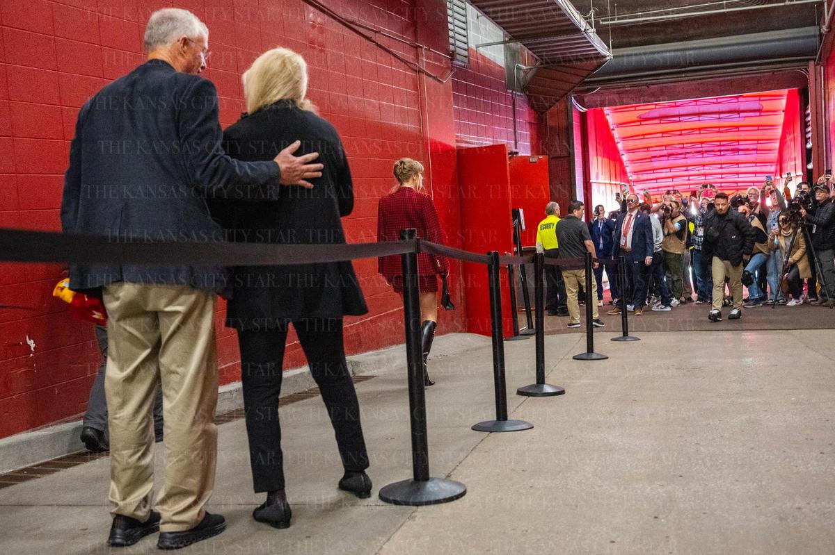 Pop star Taylor Swift’s parents watch as their daughter walks down a tunnel, escorted by security, while media swarms her for photos as she arrives for an NFL game between the Kansas City Chiefs and the Denver Broncos on Sunday, Nov. 10, 2024, at GEHA Field at Arrowhead Stadium.