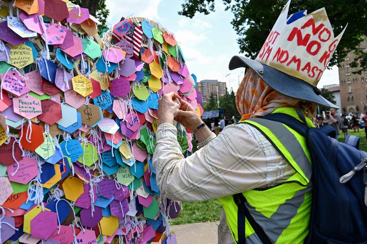 A protester at the “No Kings” rally places a message on the Intention Heart art installation at Mill Creek Park on Saturday, June 14, 2025, in Kansas City. The display was by artist Eugenia Ortiz and was meant to collect the positive intentions of people at the event.