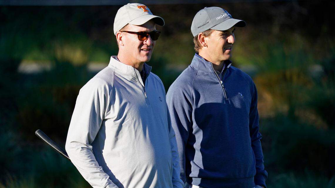 FILE - In this Feb. 6, 2020 file photo, Peyton Manning, left, and his brother Eli Manning wait to hit from the first tee of the Spyglass Hill Golf Course during the first round of the AT&T Pebble Beach National Pro-Am golf tournament in Pebble Beach, Calif. Both Mannings have become deejays. The former quarterbacks, two-time Super Bowl-winning brothers and close mates with Kenny Chesney, kicked off the “Poets & Pirates DJ Sessions” this week on the singer’s SiriusXM channel, No Shoes Radio. In addition to spinning the songs, the Mannings told stories about their personal meanings, as well as about their long-time friendships with Chesney. (AP Photo/Tony Avelar, File)