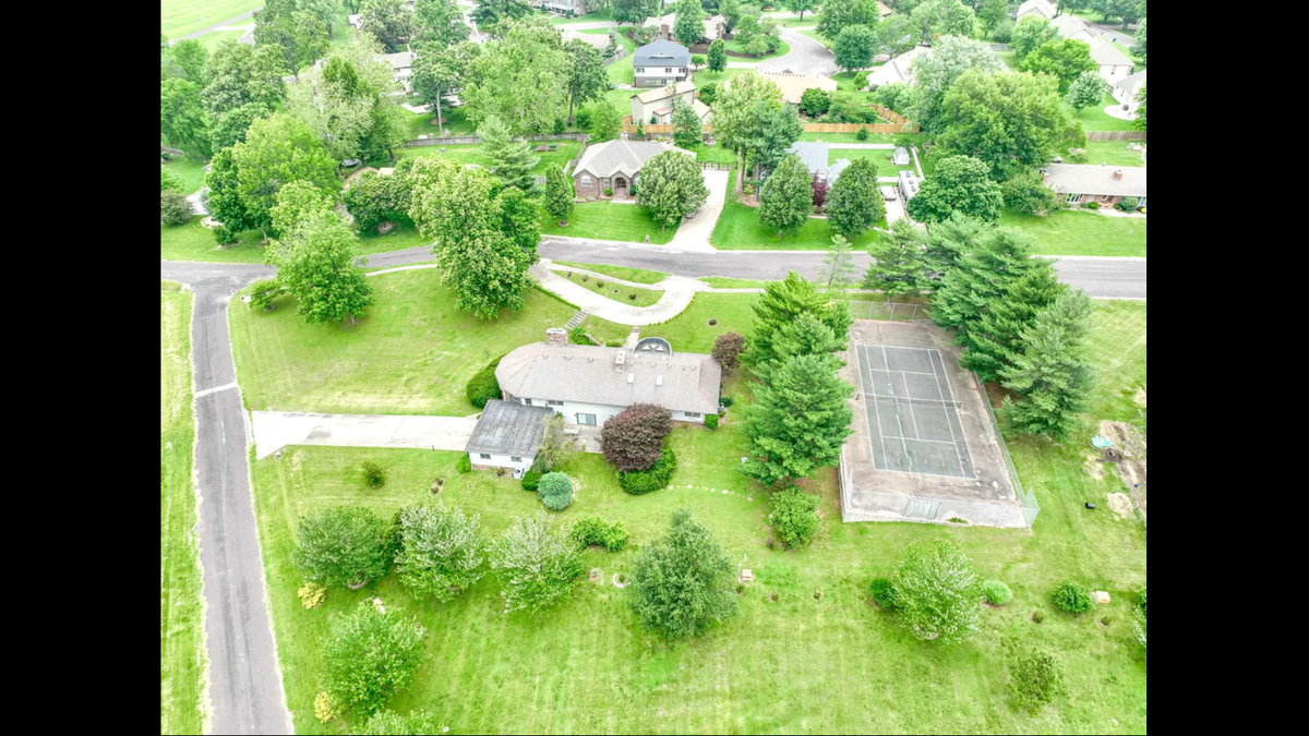 An aerial view of the home at 423 N. Belaire St. in Monett, Missouri shows a large deck and a personal tennis court.