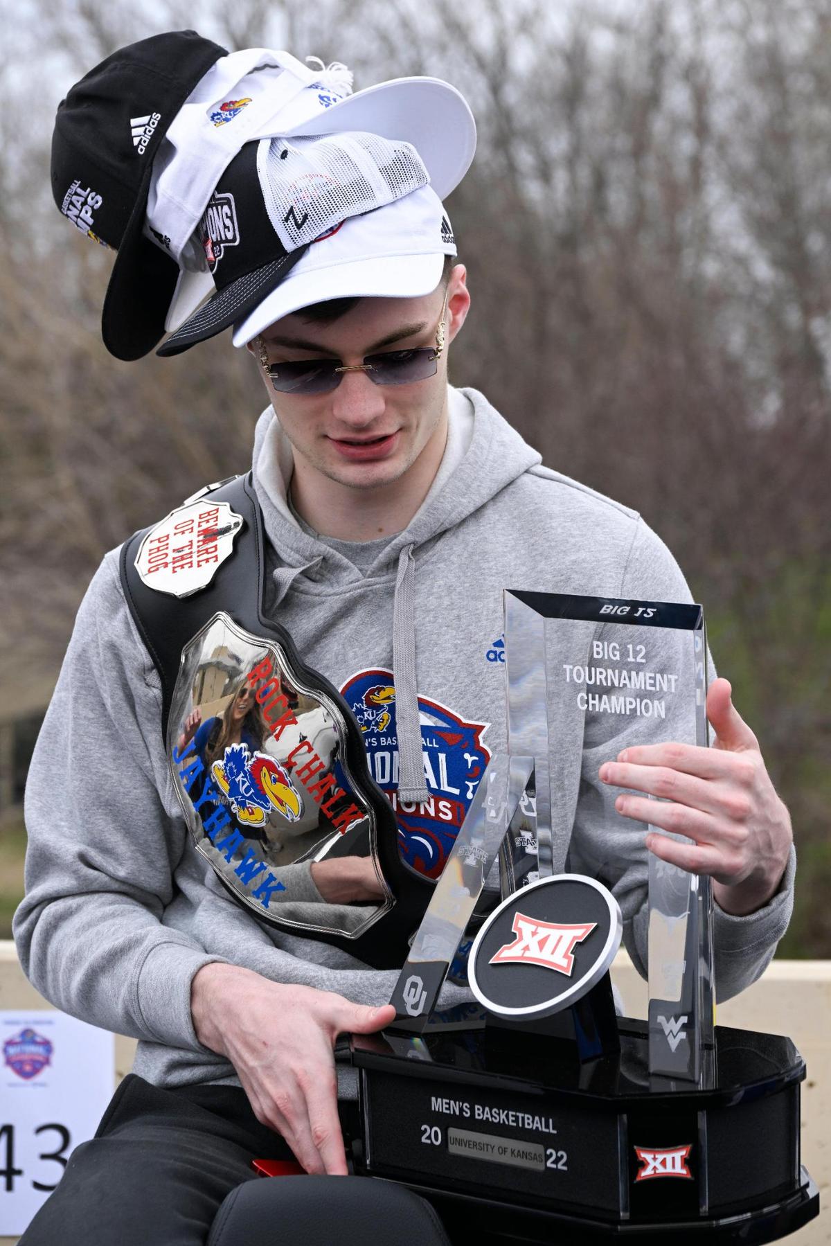 Kansas guard Christian Braun posed with some of the hardware from their championship season, and a stack of hats, before the Jayhawks parade Sunday in Lawrence.