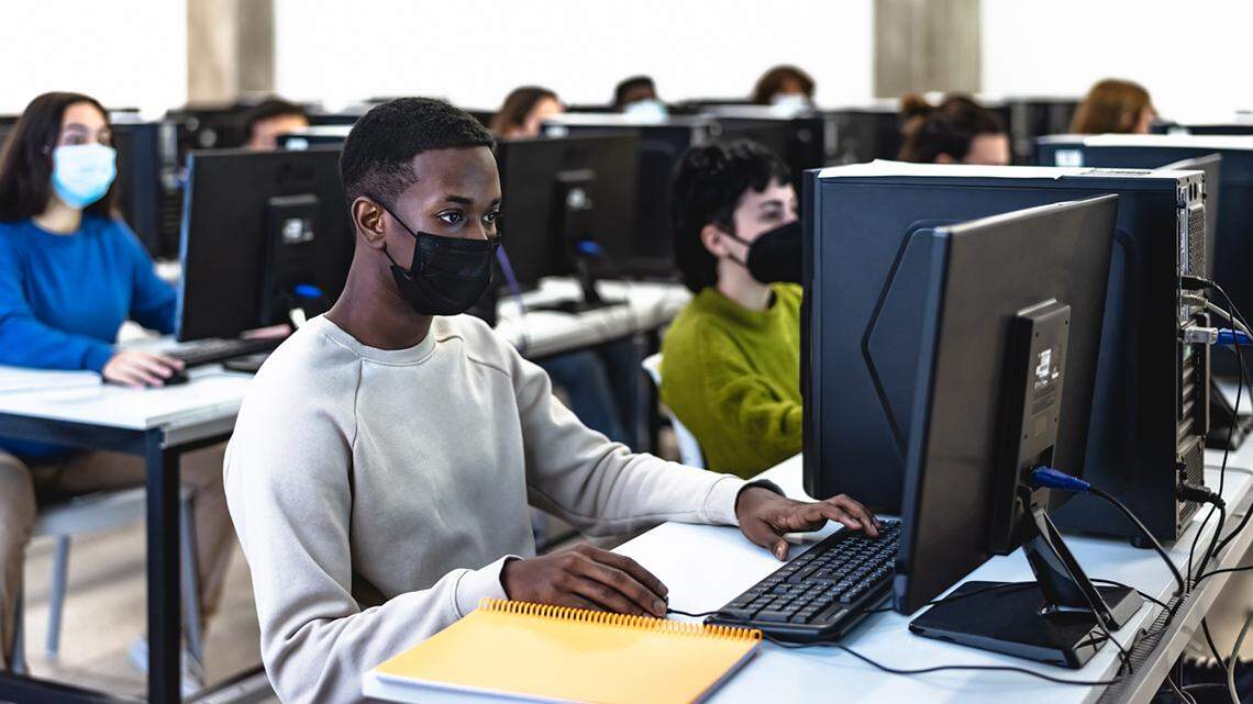 Young students taking an exam in high school while wearing face mask during coronavirus pandemic - Education technology COVID-19 mandate