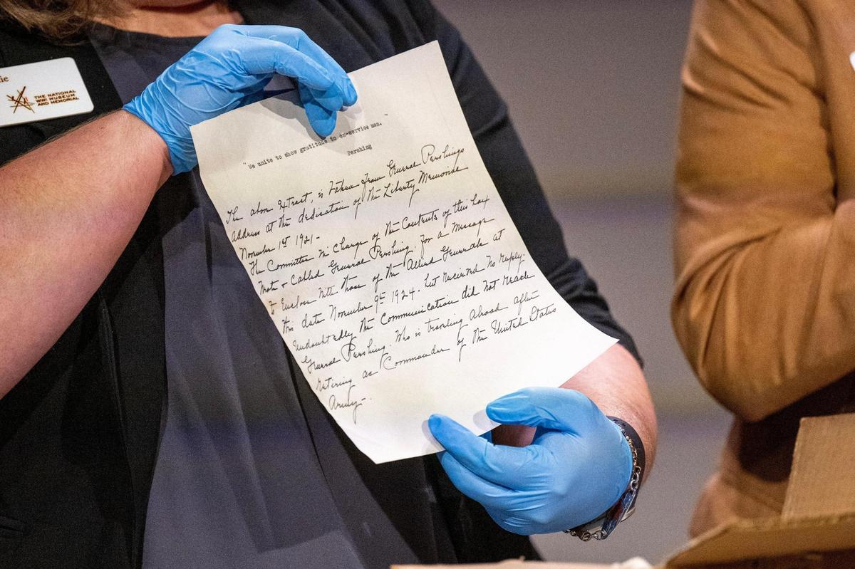 Stacie Peterson, director of exhibitions and collections at the National WWI Museum and Memorial, shows an historical office memo during the unveiling ceremony of a 100-year-old time capsule at the museum on Wednesday, Oct. 16, 2024, in Kansas City.