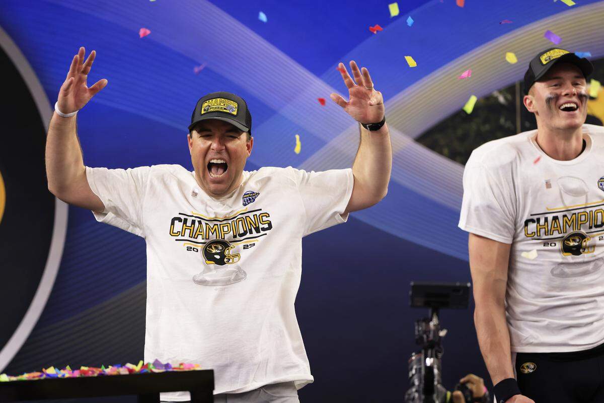Coach Eliah Drinkwitz and Brady Cook #12 of the Missouri Tigers celebrate after defeating the Ohio State Buckeyes 14-3 in the Goodyear Cotton Bowl at AT&T Stadium on December 29, 2023 in Arlington, Texas.