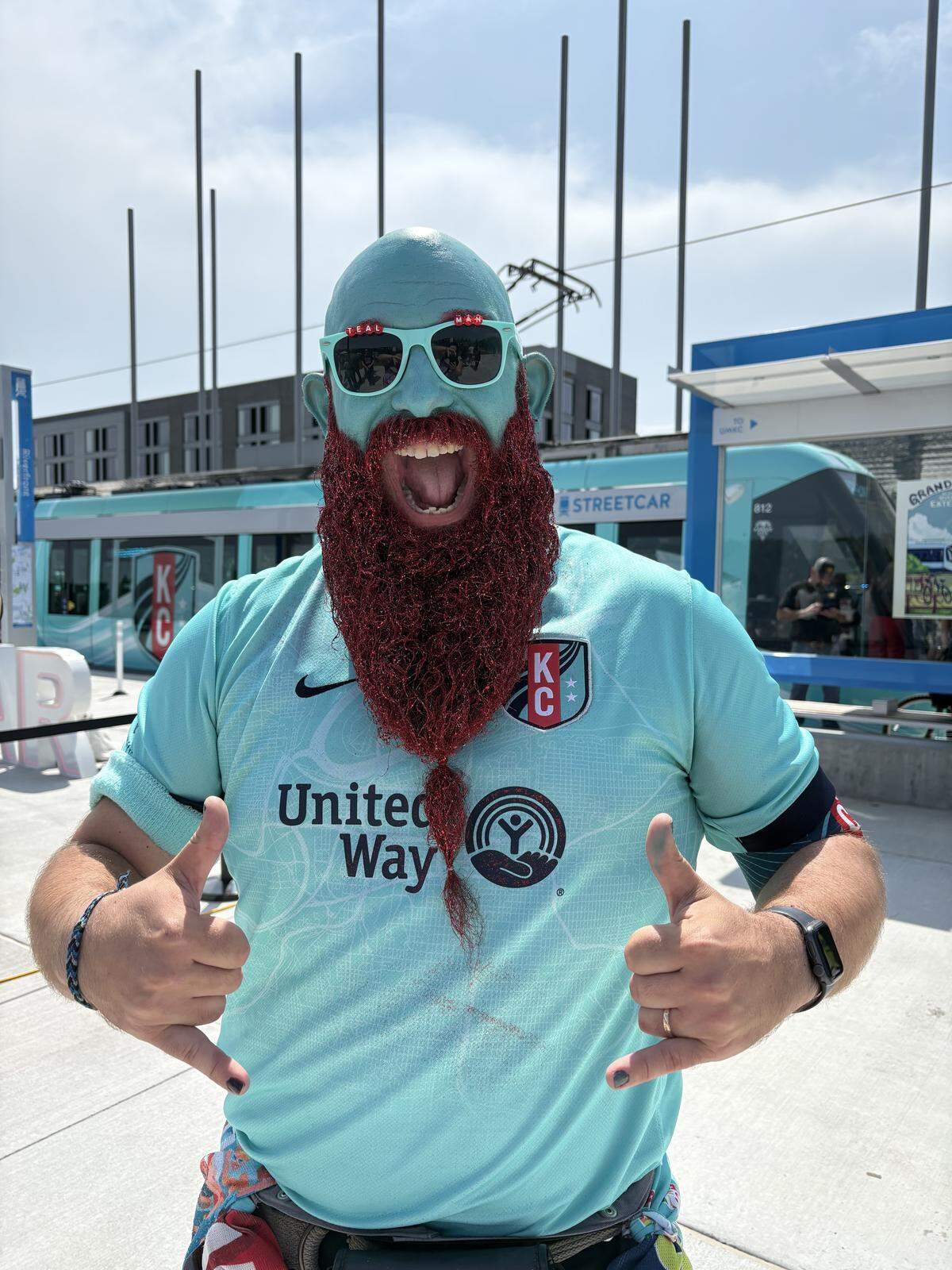 Richard Harper, better known as Teal Man, poses for a photo in front of the Kansas City Streetcar near CPKC Stadium. A Plaza resident, Harper says he plans on taking the newly-expanded streetcar to KC Current games. May 18, 2026.