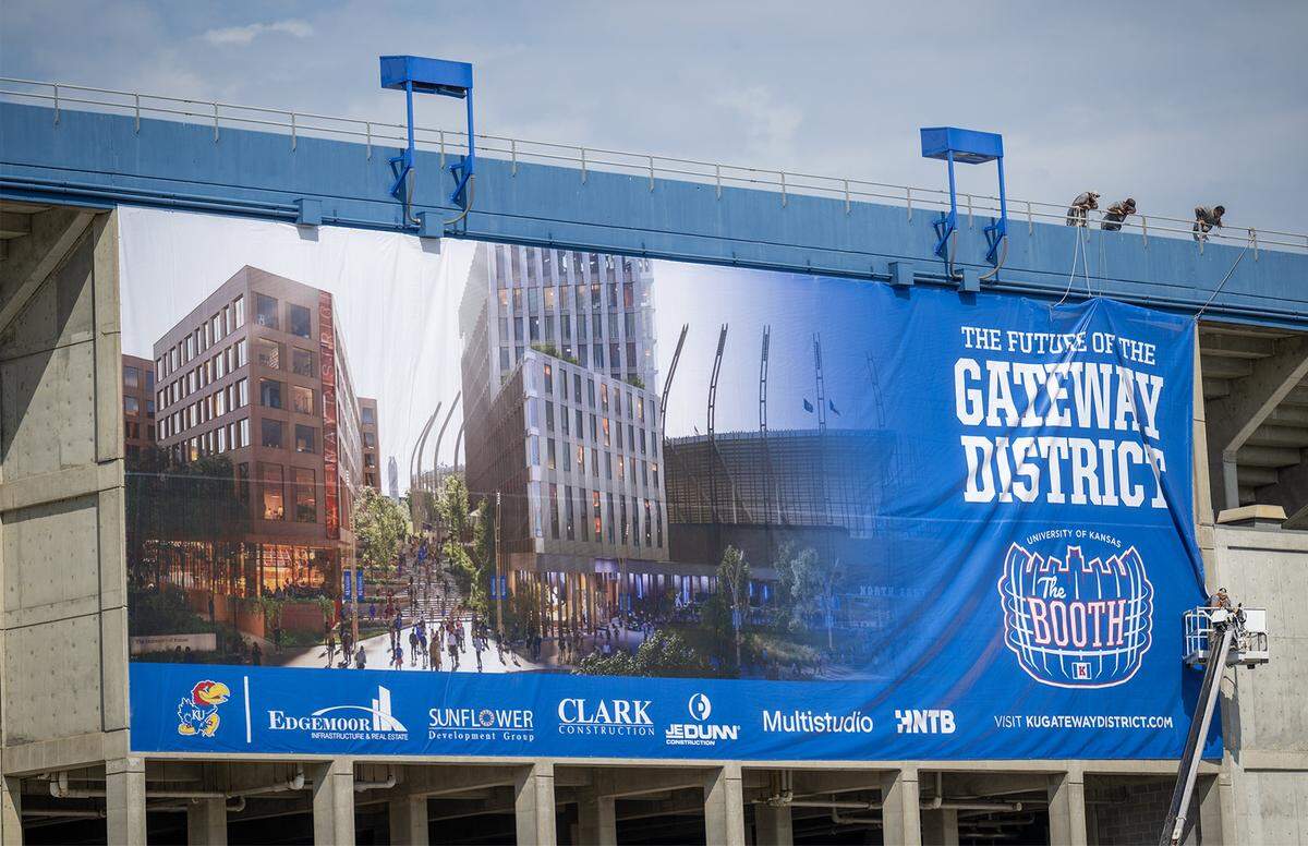 Crews hang a banner touting the future of the Gateway District as renovations at David Booth Kansas Memorial Stadium are wrapping up on Monday, August 18, 2025, in Lawrence. The Kansas Jayhawks host Fresno State on Saturday, August. 23, 2025, in the home opener at the renovated facility at the University of Kansas in Lawrence, Kansas.