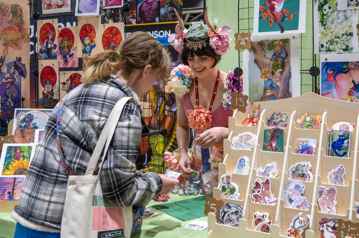 Maeson Chilton helps a customer at her artist booth during Planet Comicon at the Kansas City Convention Center on Saturday, March 22, 2025.