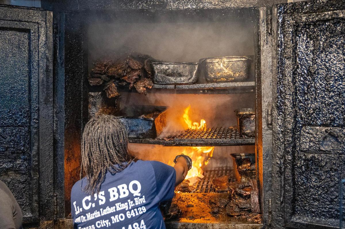LC’s Bar-B-Q owner Tausha Hammett sprays down the smoking pit. It’s the smoke that contributes to the meat’s texture and flavor.