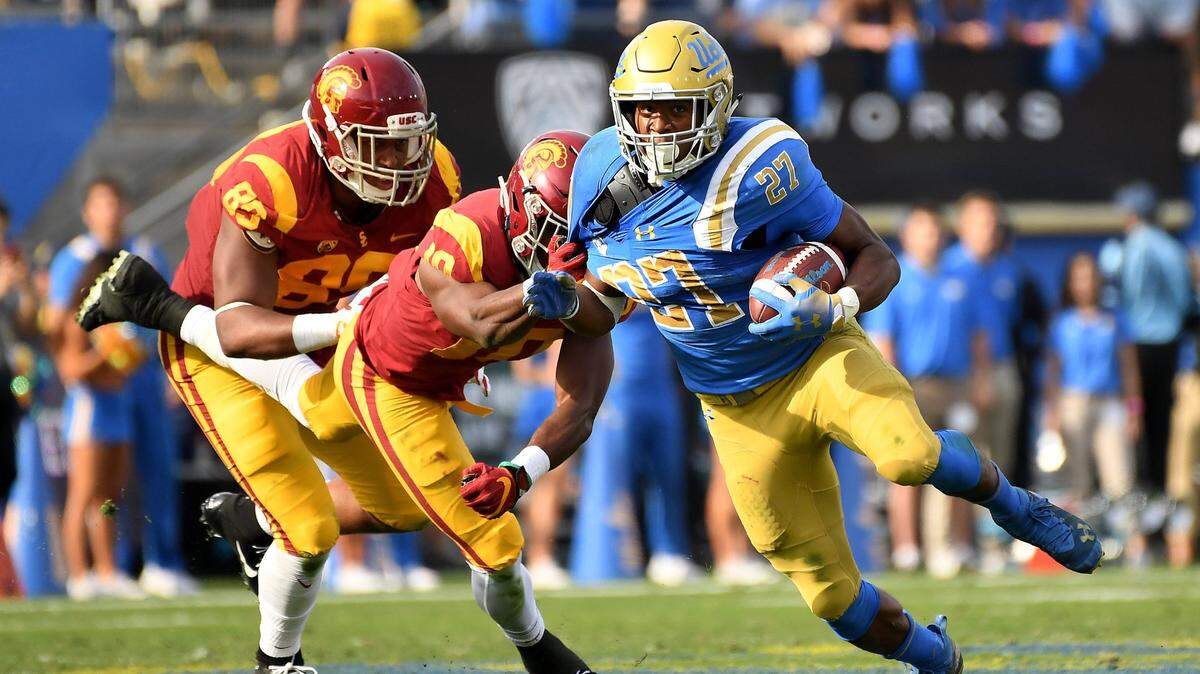 UCLA running Joshua Kelley, right, is brought down by USC linebacker John Houston during a 2018 game at the Rose Bowl in Pasadena, Calif.