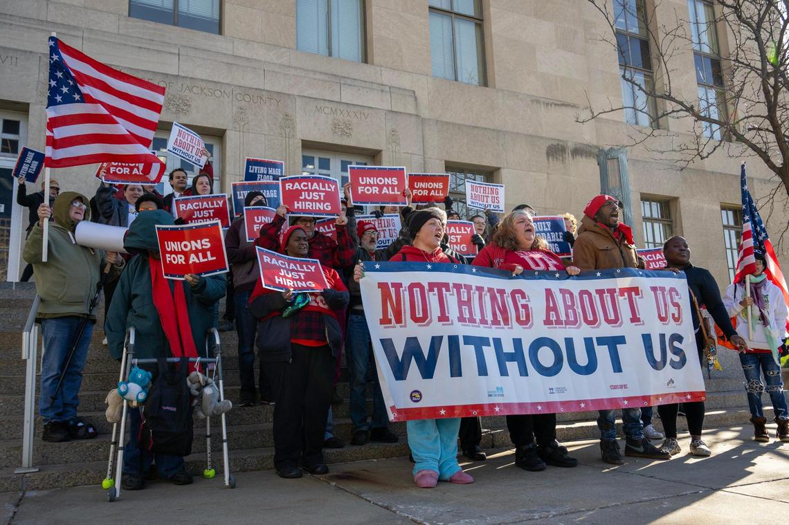Community members chant and hold up signs on the steps of the Jackson County Courthouse on Monday, Dec. 18, 2023, in Kansas City. Low-wage workers objected to public funding for a new Royals stadium without a strong Community Benefits Agreement ensuring living-wage jobs and affordable housing.