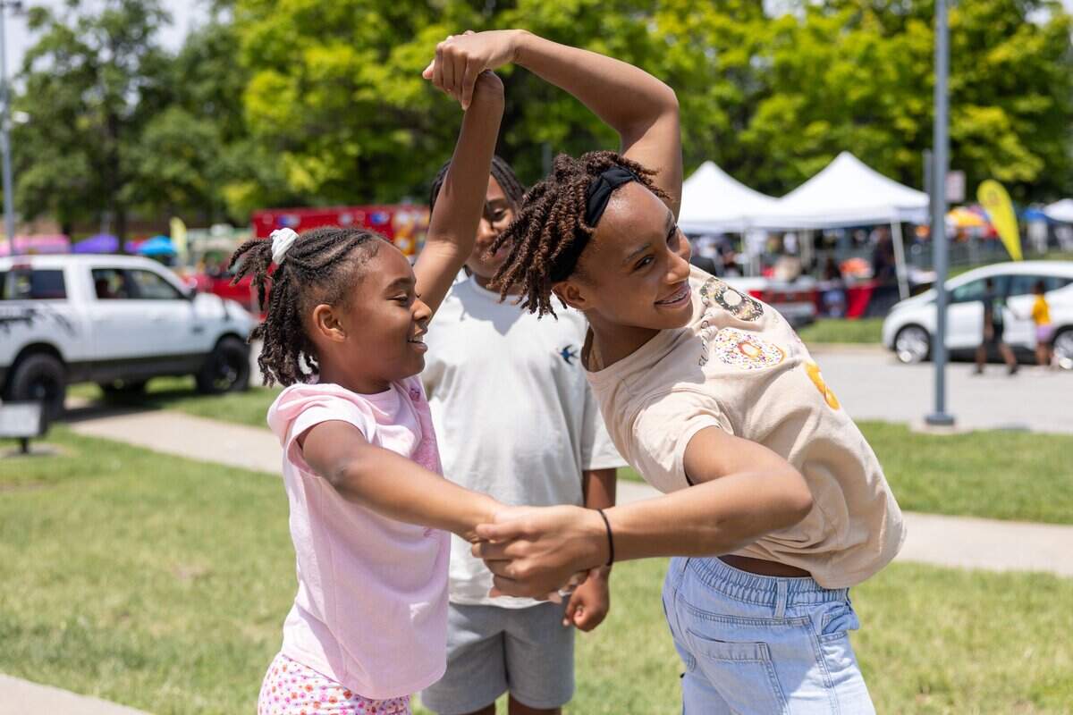 Gia Morrow, nine, left, and Charleigh Bush, 12, spin each other around during JuneteenthKC 15th Annual Heritage Festival at E 18th Street on Saturday, June 20, 2026.