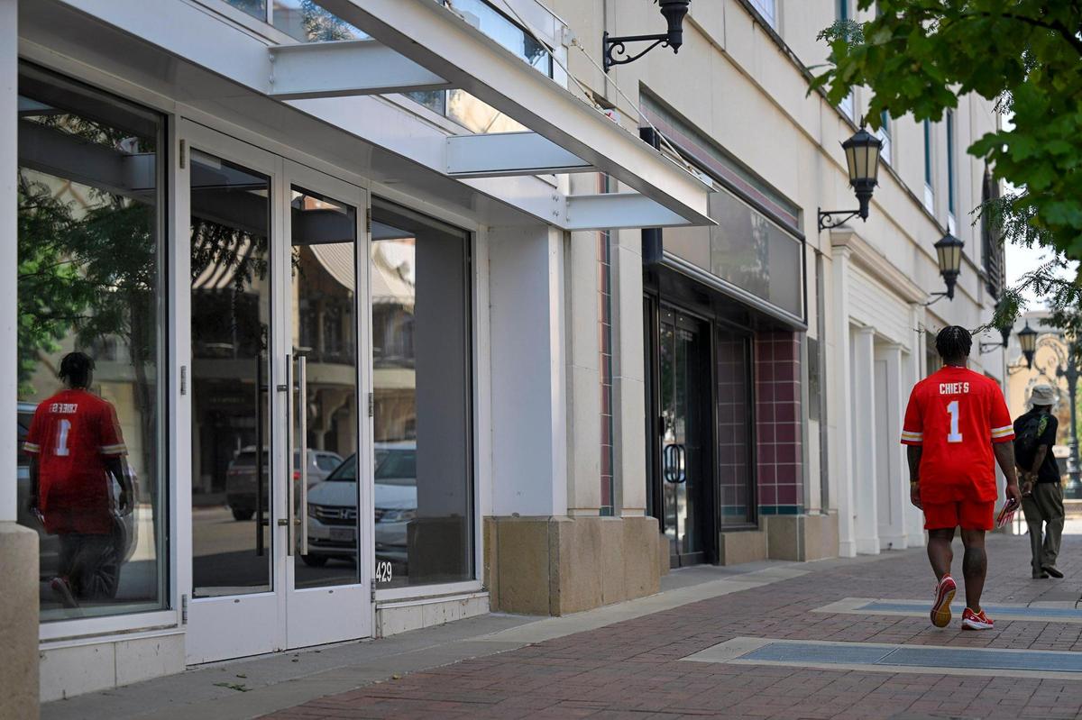 Pedestrians walk past a line of empty storefronts on Nichols Road at the Country Club Plaza.