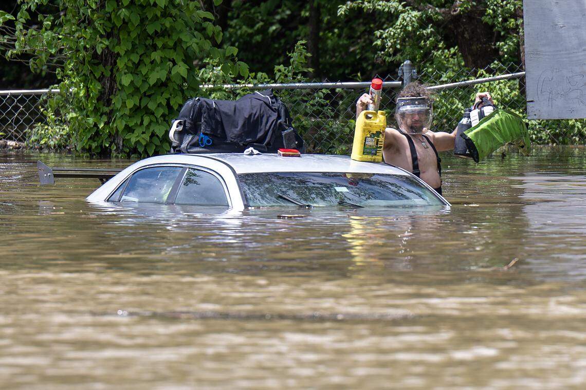 A person walks in flooding waters near the Fisca gas station at the corner of Old 23 Street and Television Place on Monday, April 27, 2026, in Kansas City.