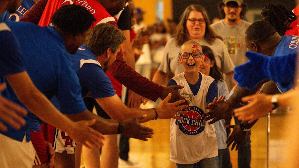 Ember Henry, 10, high-fives former Kansas Jayhawks basketball players before the playing of the annual Rock Chalk Roundball Classic charity hoops game on Thursday, June 4, 2026, at Free State High School in Lawrence, Kansas.
