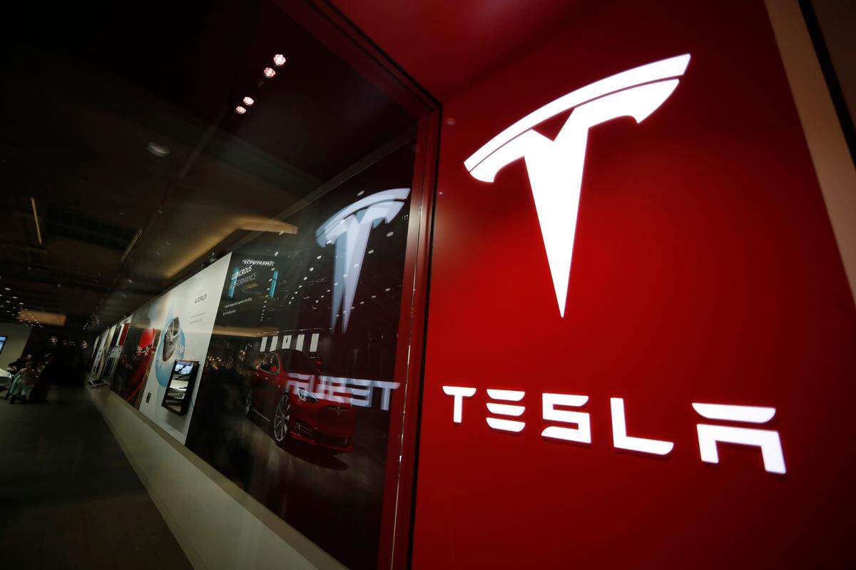 FILE - A sign bearing the company logo outside a Tesla store in Cherry Creek Mall in Denver, Feb. 9, 2019. Tesla is recalling nearly nearly 595,000 vehicles in the U.S., Thursday, April 14, 2022, most for a second time, because a “Boombox” function can play sounds over an external speaker and obscure audible warnings for pedestrians. (AP Photo/David Zalubowski, File)