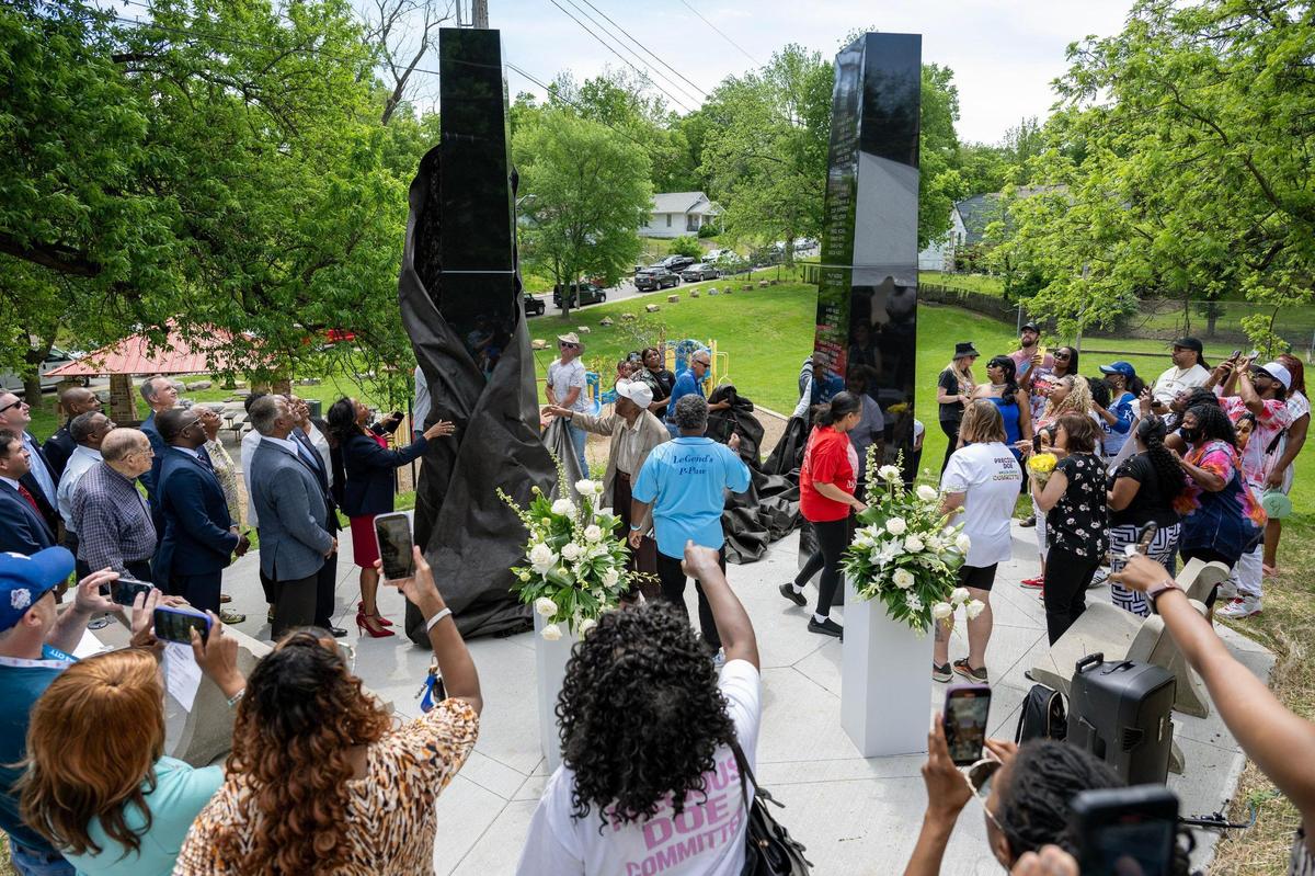 Community members gather around the Children’s Memorial as it is unveiled at Hibbs Park on Thursday, May 15, 2025, in Kansas City. The memorial honors children lost to violence between 2001 and 2024.