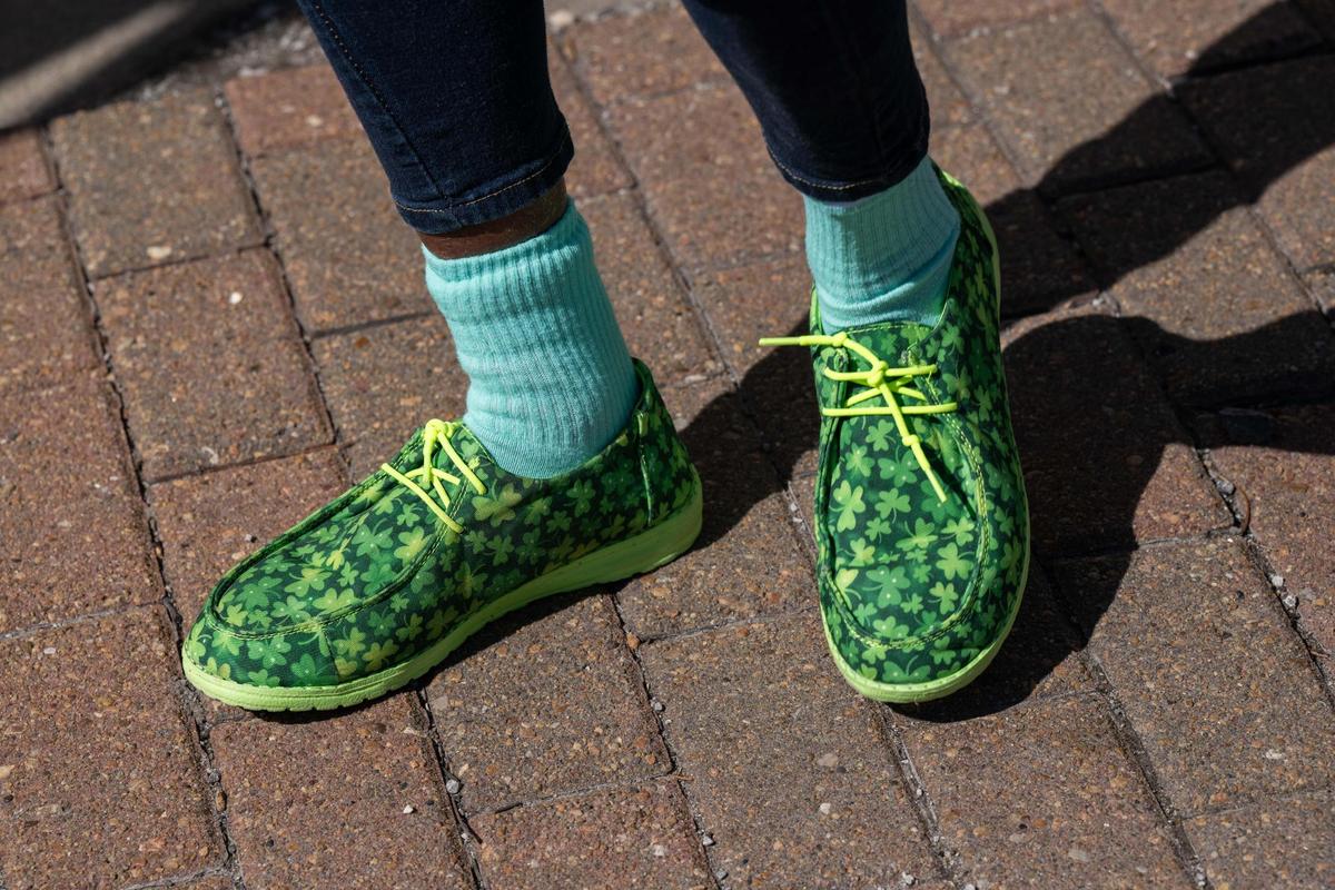 A parade attendee wearing shamrock shoes dances during the Kansas City St. Patrick’s Day Parade on Monday, March 17, 2025.
