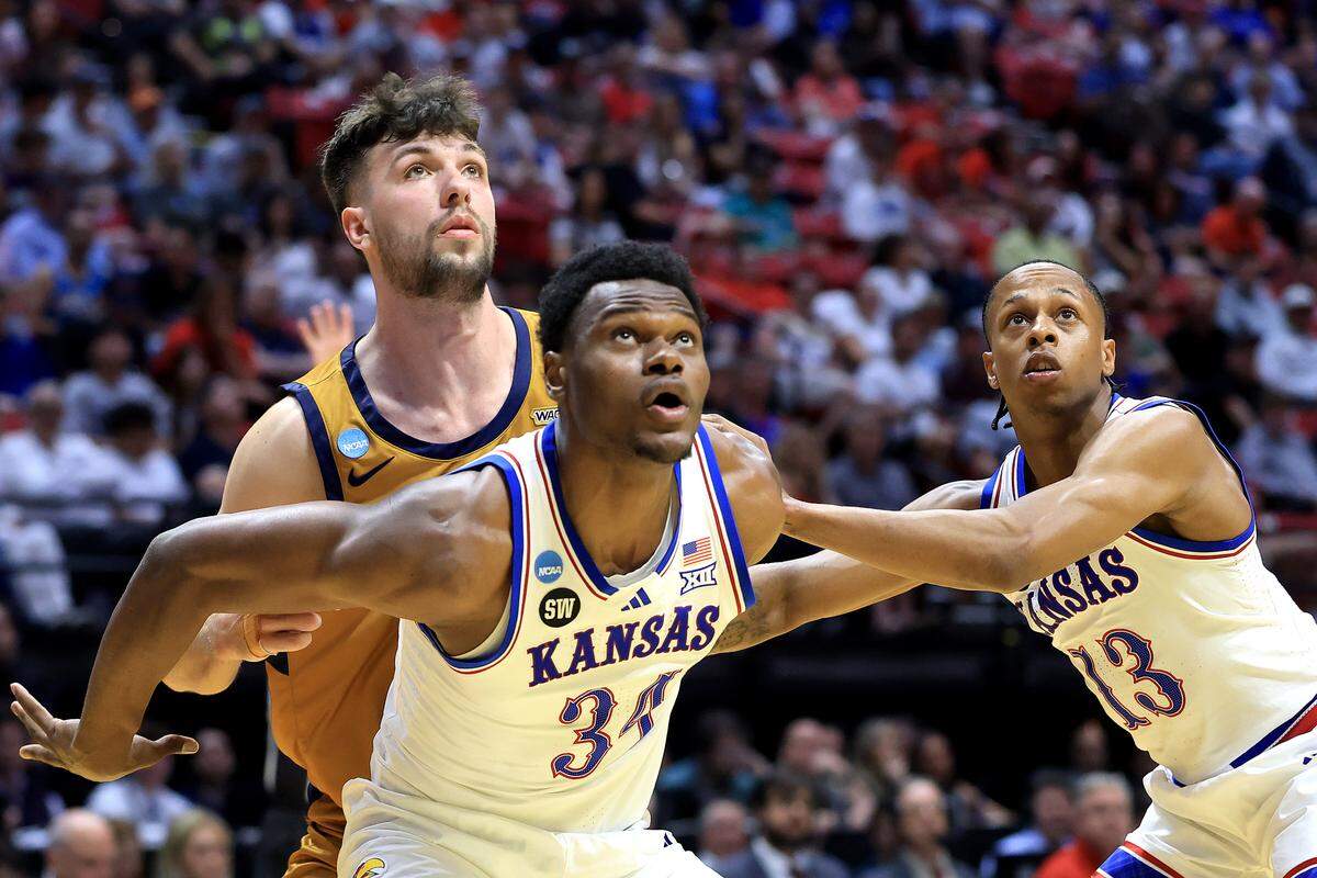 Paul Mbiya #34 and Elmarko Jackson #13 of the Kansas Jayhawks box out Bradey Henige #42 of the Cal Baptist Lancers in the first round of the 2026 NCAA Tournament at Viejas Arena on March 20, 2026 in San Diego.