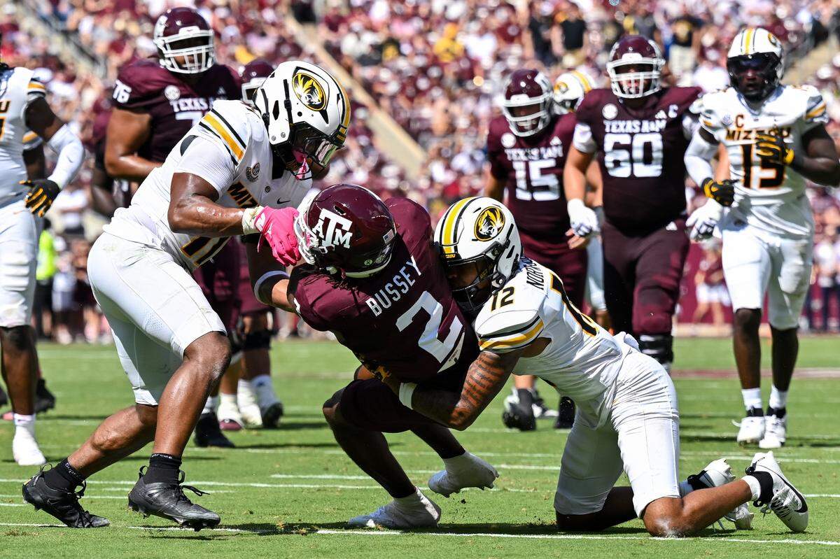 Missouri Tigers linebacker Corey Flagg Jr. (No. 11) and cornerback Dreyden Norwood (No. 12) tackle Texas A&M running back Rueben Owens during Saturday’s SEC football game at Kyle Field in College Station, Texas.