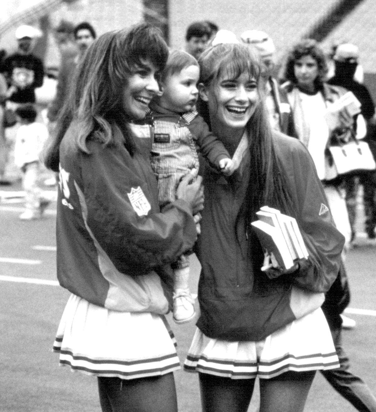 Kansas City Chiefs cheerleaders Paula Avery, left, and Jennifer Horrell pose with a young fan during a preseason event in 1991.