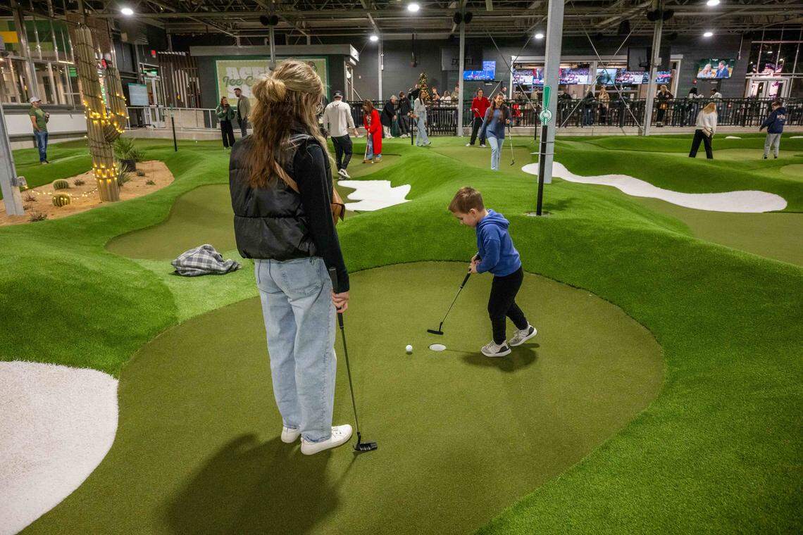 Katie Sellers and her son, Ben, 4, have a test run on the putting course at Tap-Ins at the Greenhouse, a new restaurant/mini golf concept in Overland Park, on Wednesday, December 3, 2025.