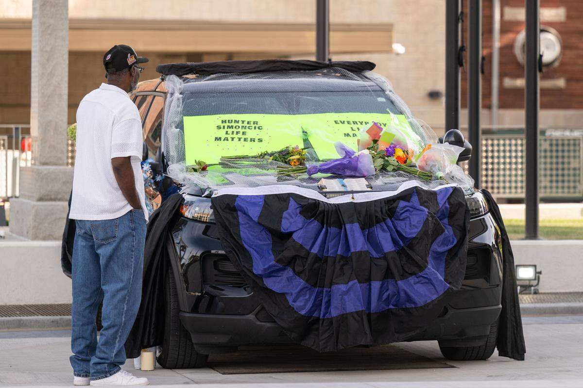 People stop to view the police cruiser driven by slain KCKPD officer Hunter Simoncic set up as a memorial in front of Kansas City, Kansas City Hall on Wednesday, Aug. 27, 2025.