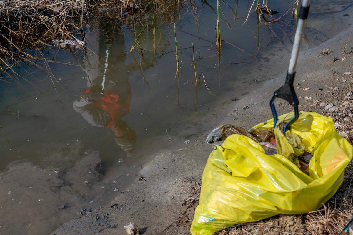 Members of Independence Together, a community service league, collect debris in yellow garbage bags along Independence Avenue on March 30.