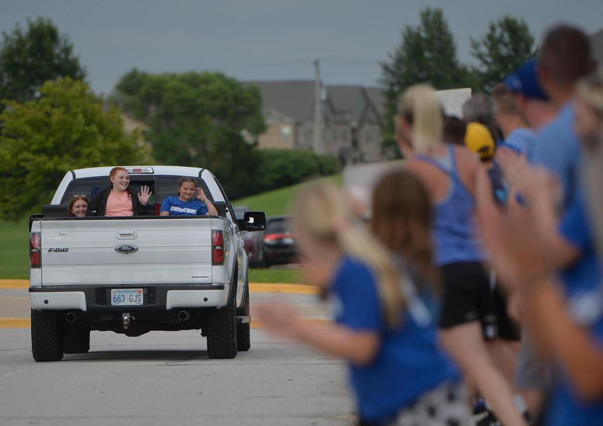 Brinley Hutson, 12, rides in the back of a truck as the community welcomes her, Monday, July 12, 2021 at California Trail Middle School in Olathe. This is the first time she has seen some friends, coaches and community members since having surgery.