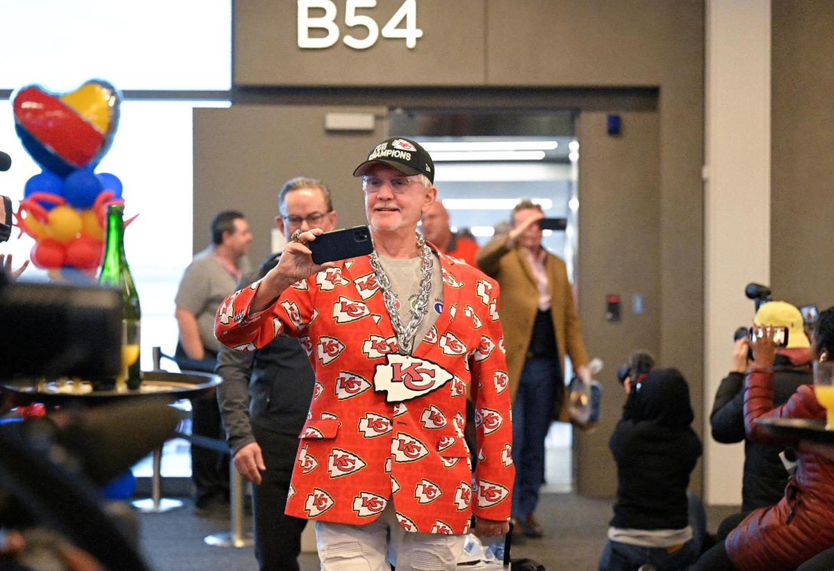 Gary Morsch eyes a glass of champagne as he deplanes a Southwest Airlines flight from Chicago which was the first to land on Tuesday, Feb. 28, 2023, at the new $1.5 billion single terminal at Kansas City International Airport.