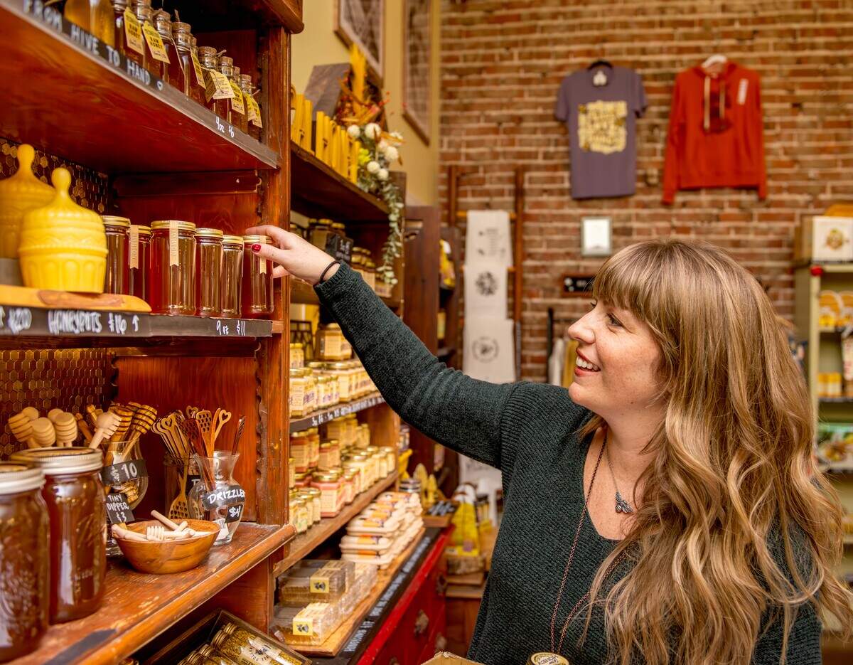 Rachael Messner, one of the owners of Messner Bee Farm Store in downtown Lee’s Summit, puts honey on a shelf.