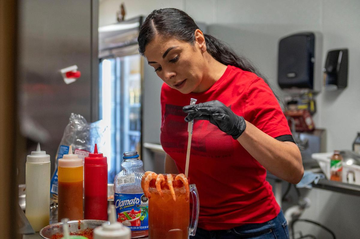 Jenny Barraza, co-owner of Micheladas Culiacán, prepares the restaurant’s signature michelada drink. She loads them with shrimp, curling around the rim of the glass, and beef jerky.