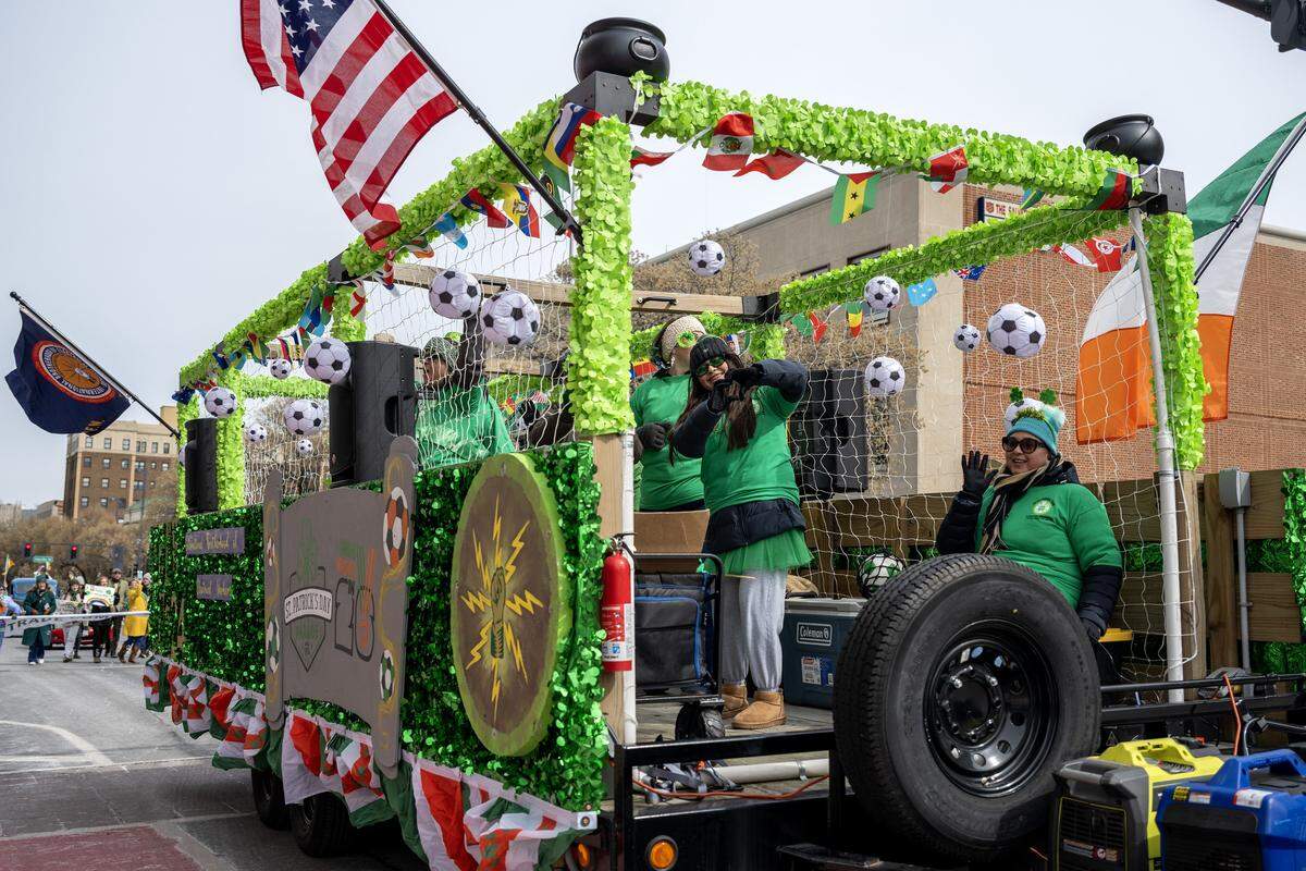 A float by the International Brotherhood of Electrical Workers, decorated with soccer balls and international flags rides along Broadway Boulevard during the St. Patrick's Day parade on Tuesday, March 17, 2026, in Kansas City.