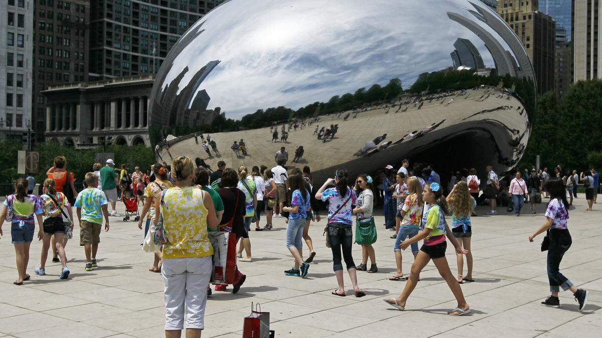 In this Wednesday, June 13, 2012, photo, visitors at Chicago’s Millennium Park enjoy the sculpture “Cloud Gate,” also known as “The Bean.”