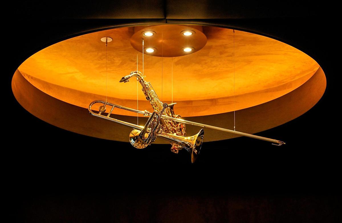Jazz-inspired decor, including a light fixture made of musical instruments, hangs in the theater room of Three Light Luxury Apartments.