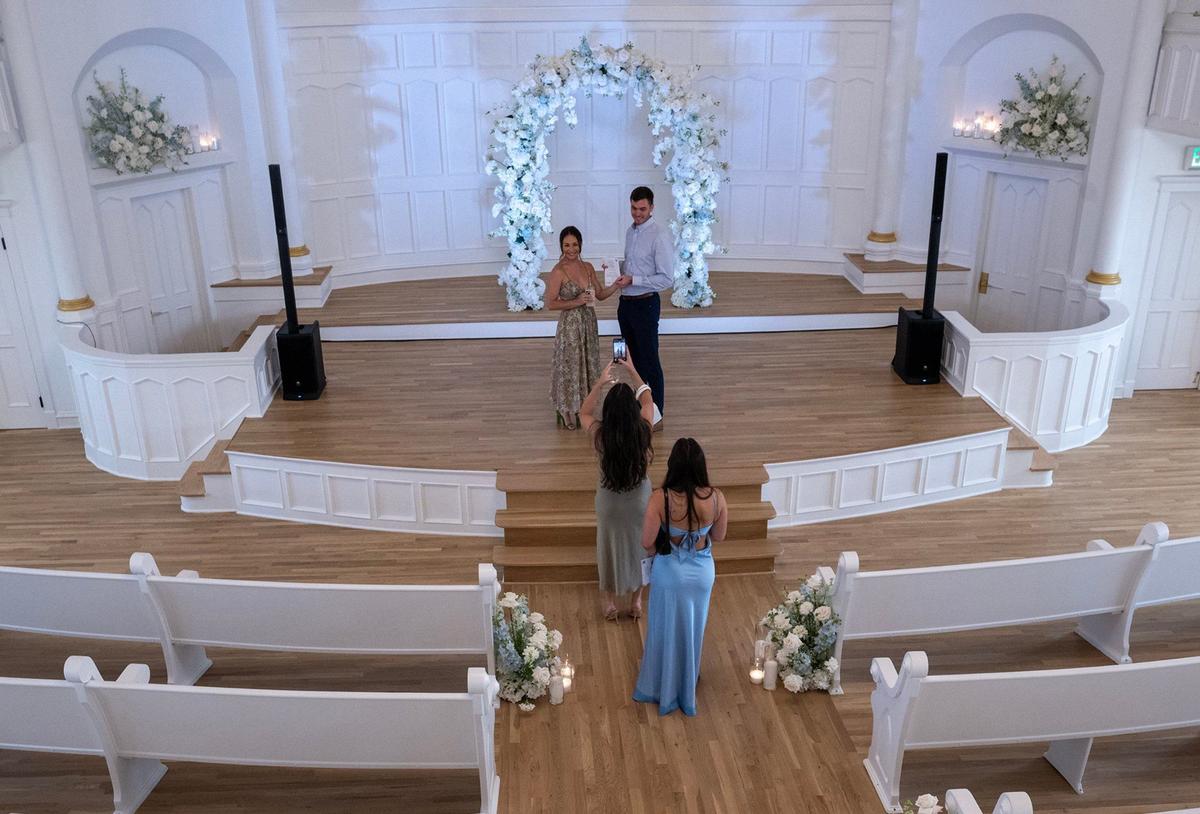 Bride-to-be Faith Connelly, lower, center, and her fiancé, Andrew Martin, both of Kansas City, have their photo taken at Melrose Abbey, where they will wed on Dec. 31. The couple, along with family members Halle Connelly, in blue, and Ashle Olivas, were on hand for the grand opening on Thursday.
