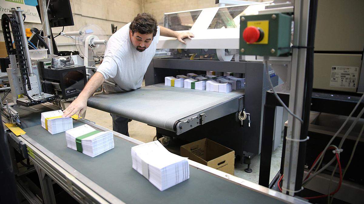 Eddy Estrada sends stacks of freshly cut mail-in ballots at a Florida Internal Services Department print shop.
