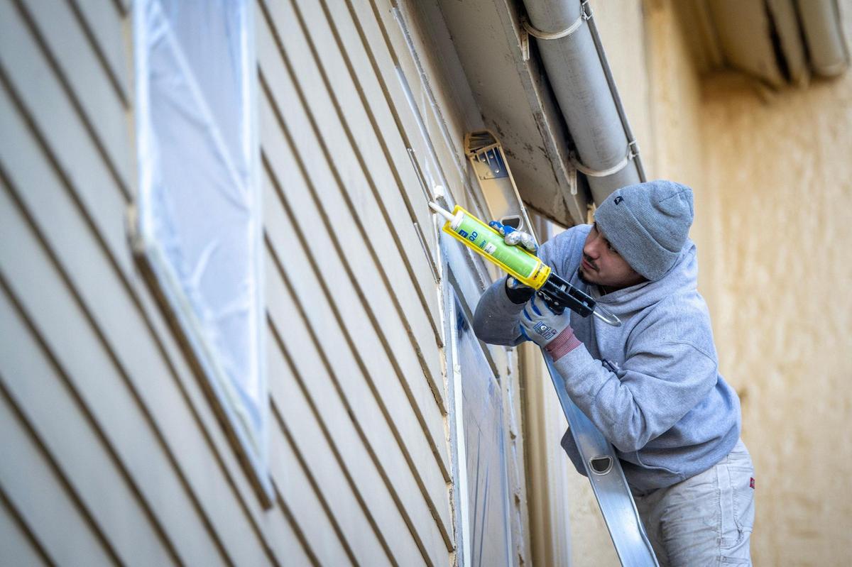 A worker caulks siding at 620 Scott Ave. at Fort Leavenworth. The home, which dates to about 1870, will undergo major renovation as part of a sweeping historic restoration plan on the post.