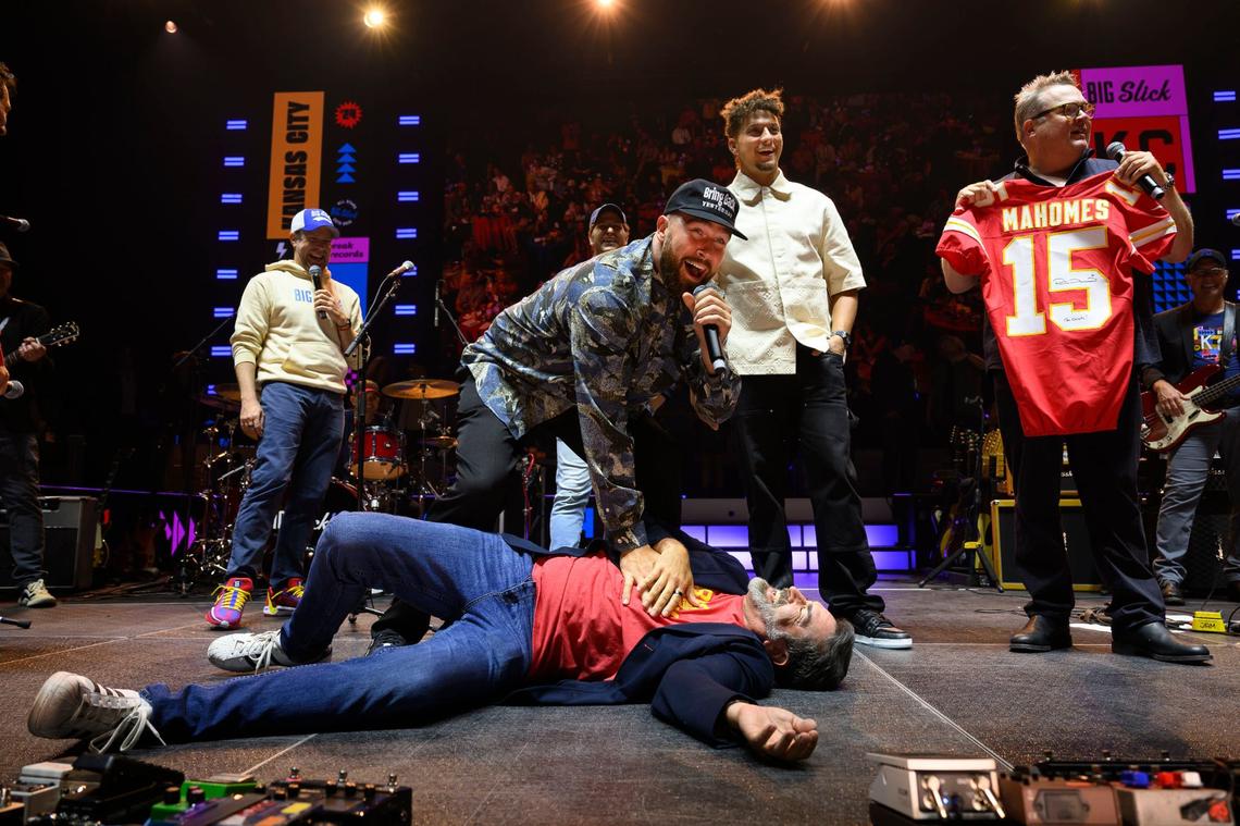 Travis Kelce tends to Rob Riggle after he “collapsed” because an NFL package sold for $250,000 during the Big Slick Party & Show on Saturday at the T-Mobile Center. To the right of Kelce are quarterback Patrick Mahomes and co-host Eric Stonestreet.