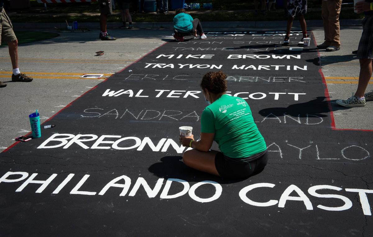 A volunteer helped paint the names of Black people who have been shot by police or others Saturday in one of the giant letters that make up the Black Lives Matter mural painted on Brookside Blvd. near 63rd St.