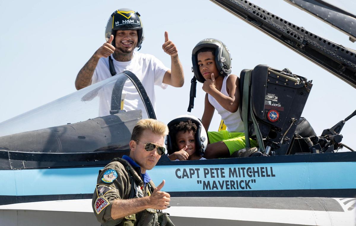 Justin Hill poses for a photo with his sons D’Million Hill, 9, and Josiah Wilkinson, 3, with a Top Gun Maverick Experience display jet during the Garmin KC Air Show on Saturday, Aug. 19, 2023, in New Century, Kan.