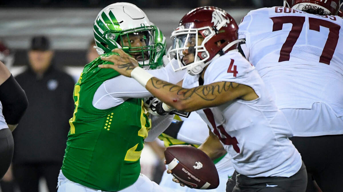Washington State quarterback Jayden de Laura (4) eludes Oregon defensive tackle Kristian Williams (91) during the fourth quarter of an NCAA college football game Saturday, Nov. 13, 2021, in Eugene, Ore. (AP Photo/Andy Nelson)