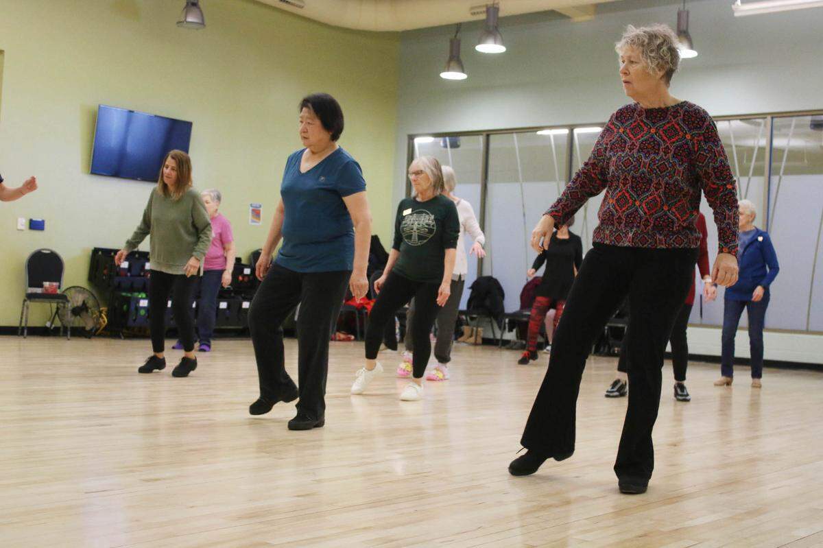 Alice Shan of Overland Park and Genie Wilcox of Olathe learn a few steps during a line dancing class at the Olathe Community Center.