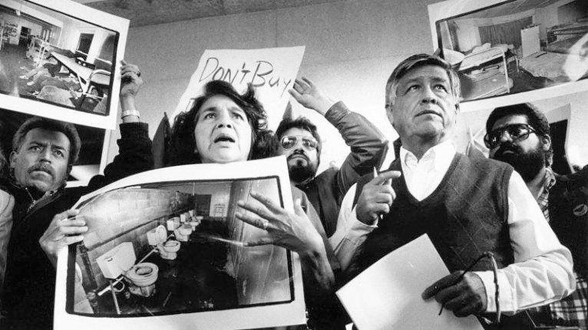 United Farm Workers leaders Dolores Huerta and César Chávez display photos of the conditions that farmworkers endure in San Joaquin Valley farm labor camps at a news conference outside U.S. District Court in Fresno, California, on Nov. 21, 1989. 