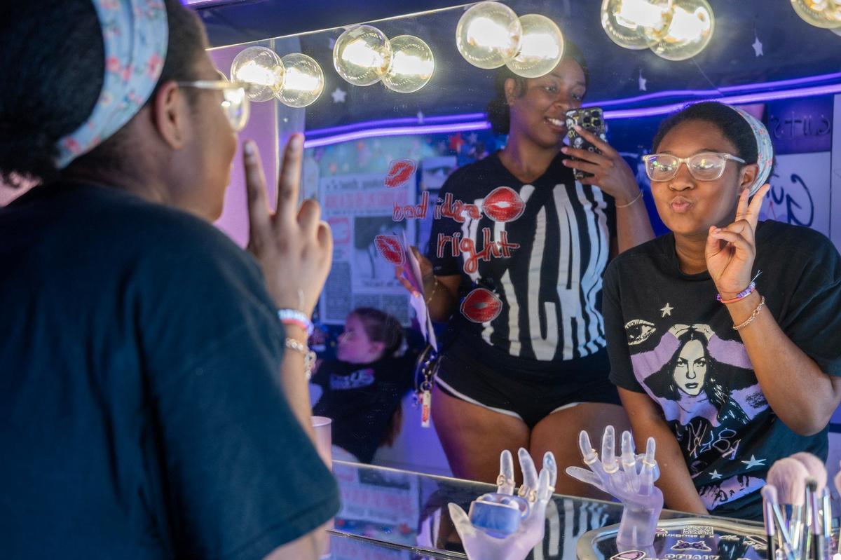 Aliyah Poole, left, takes a photo of her cousin Kassidy Poole while visiting the Olivia Rodrigo-themed bus outside T-Mobile Center.