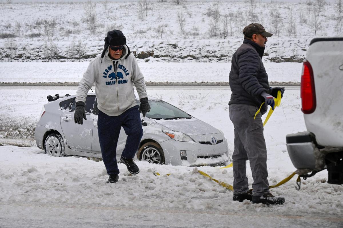 Men work to pull a car out of the ditch off of westbound K-10 Highway on Tuesday, Jan. 9, 2024, in Lenexa, Kansas. A winter storm dropped several inches of snow in the metro area leaving some roads slick and hazardous.