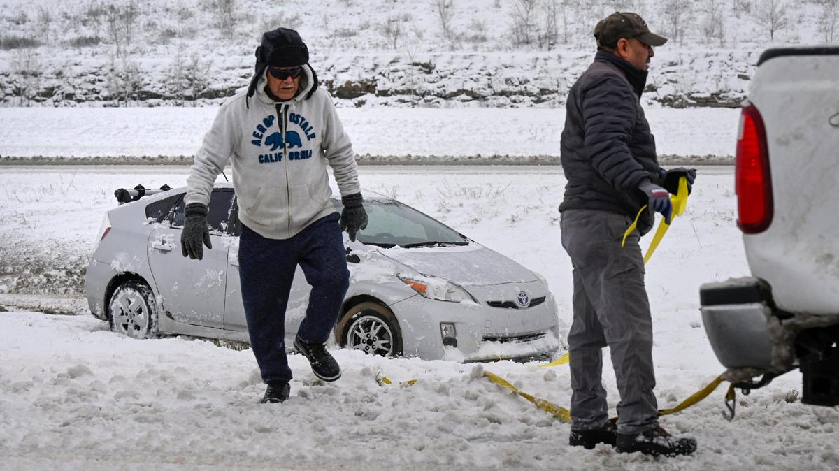 Men work to pull a car out of the ditch off of westbound K-10 Highway on Tuesday, Jan. 9, 2024, in Lenexa, Kansas. A winter storm dropped several inches of snow in the metro area leaving some roads slick and hazardous.