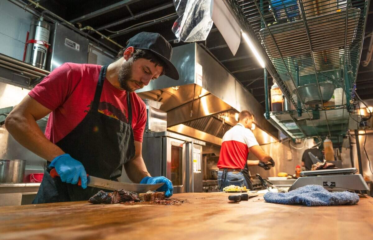 Kitchen manager Cruz Barnes cuts up chunks of burnt ends Thursday at Wolfepack BBQ in Columbus Park. The newly opened barbecue restaurant features brisket, burnt ends, ribs, and other barbecue staples.