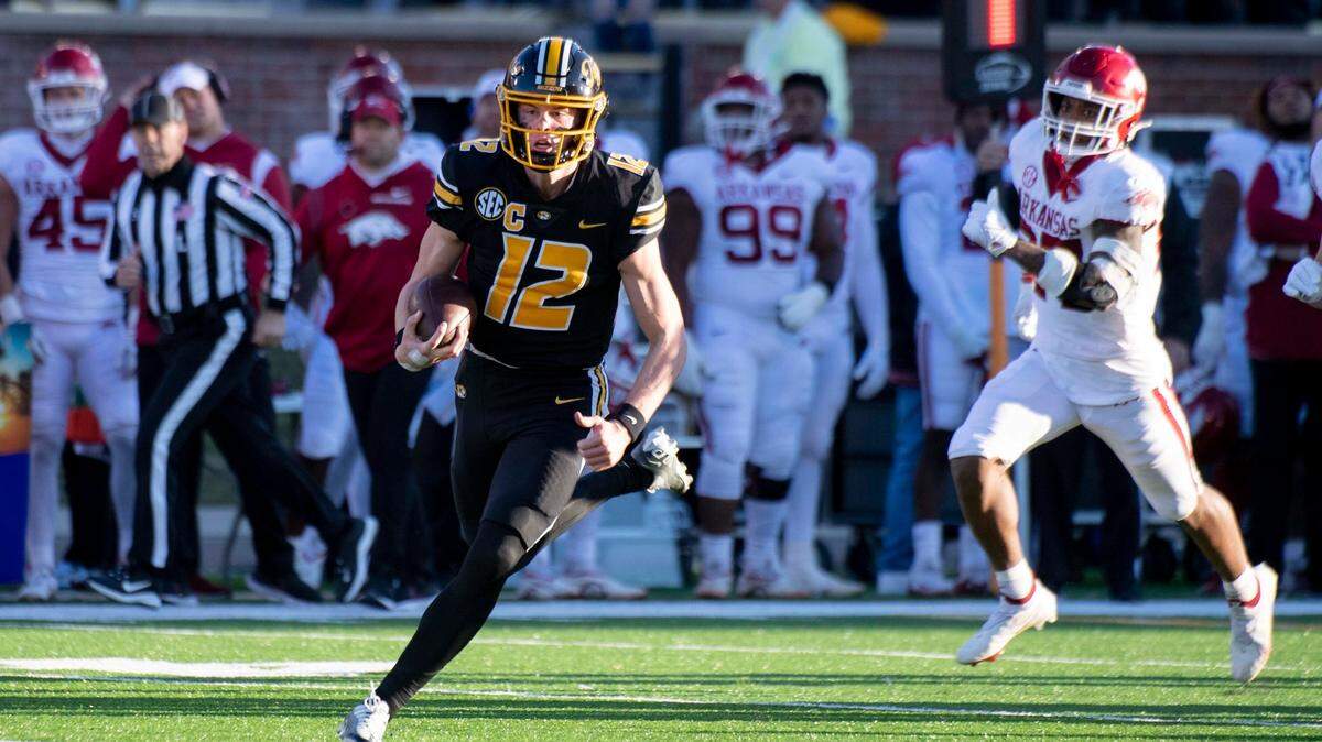 Missouri quarterback Brady Cook (left) runs past Arkansas linebacker Chris Paul Jr. during the second quarter on Friday in Columbia, Mo.
