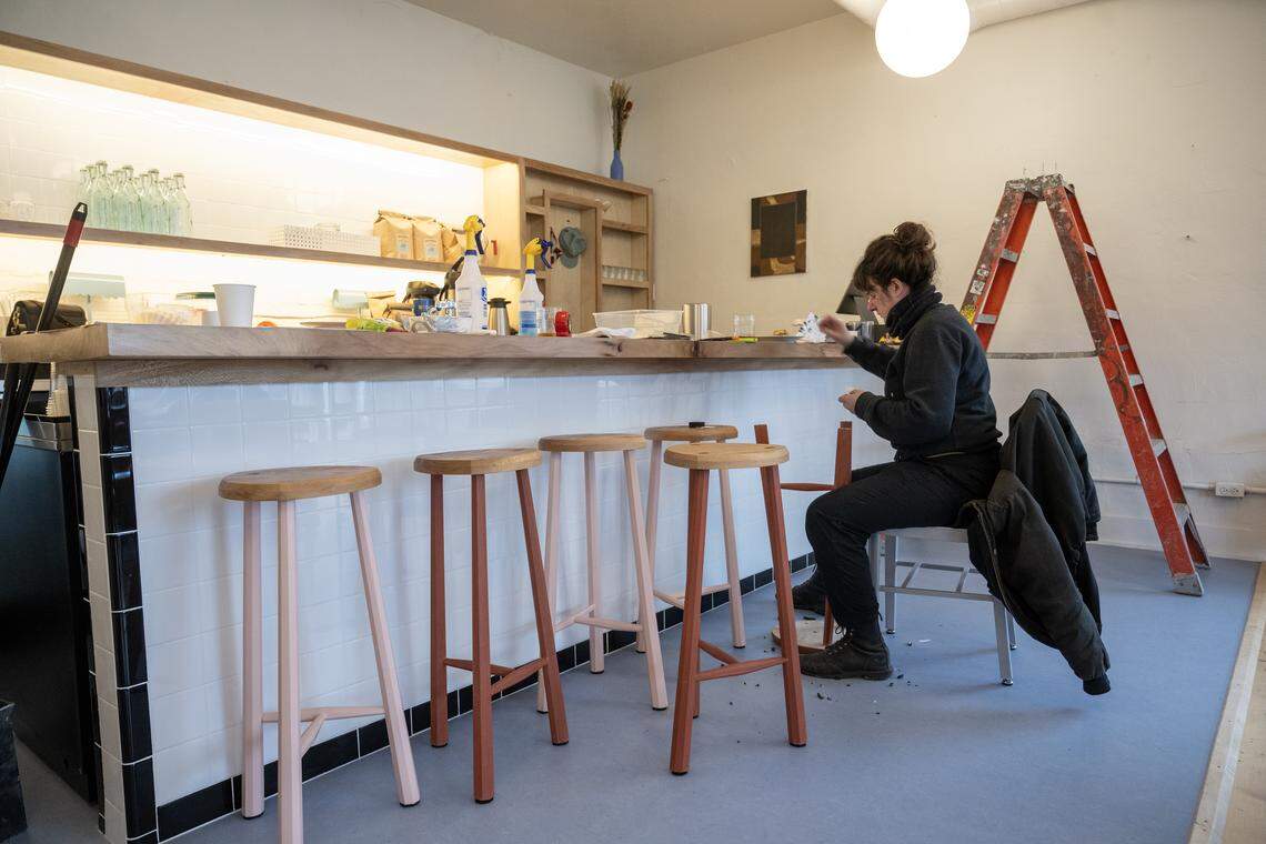 Woodworker Grace Ambrose adds felt pads to custom sycamore and oak stools she built for Dear Donna, a new restaurant concept opening in the former Happy Gillis space at 549 Gillis St. in Columbus Park. Ambrose was working on Tuesday, March 3, 2026, at the restaurant which plans to open sometime in March. 