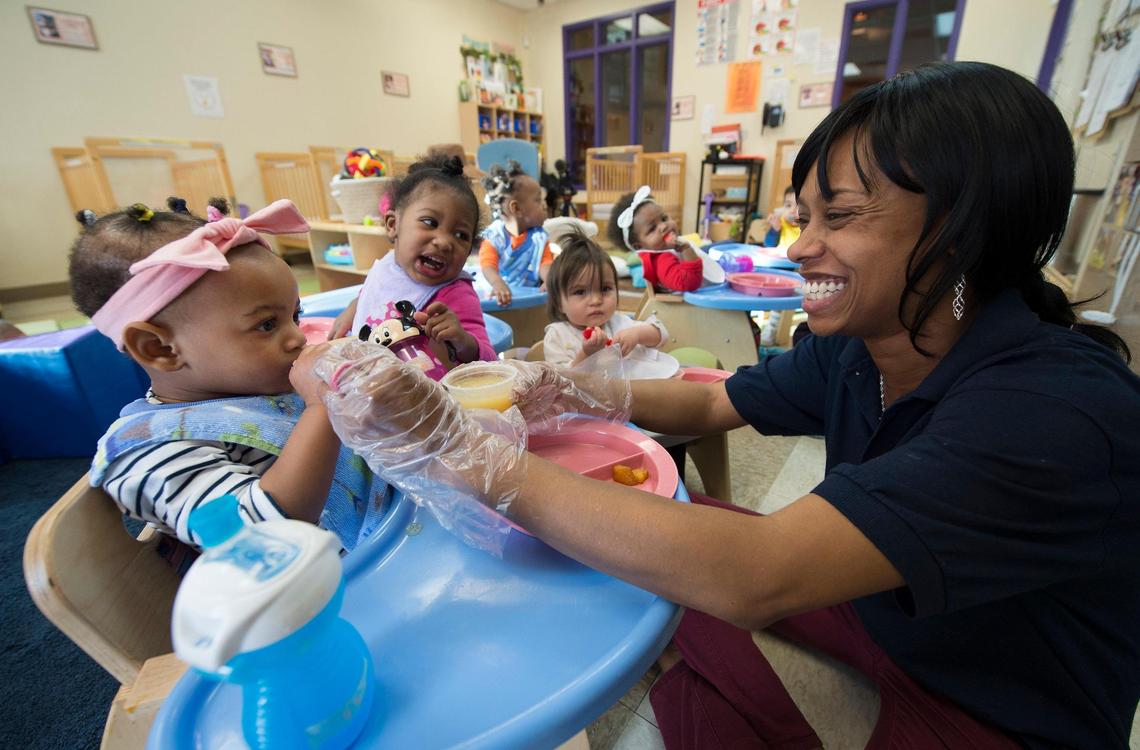 Niqui Hill, a lead teacher in the St. Mark Center infant classroom, helps 18-month-old Za’Niya with her breakfast. “Pre-K is the stepping-stone for kindergarten and beyond,” Hill said. “It makes a world of difference.”